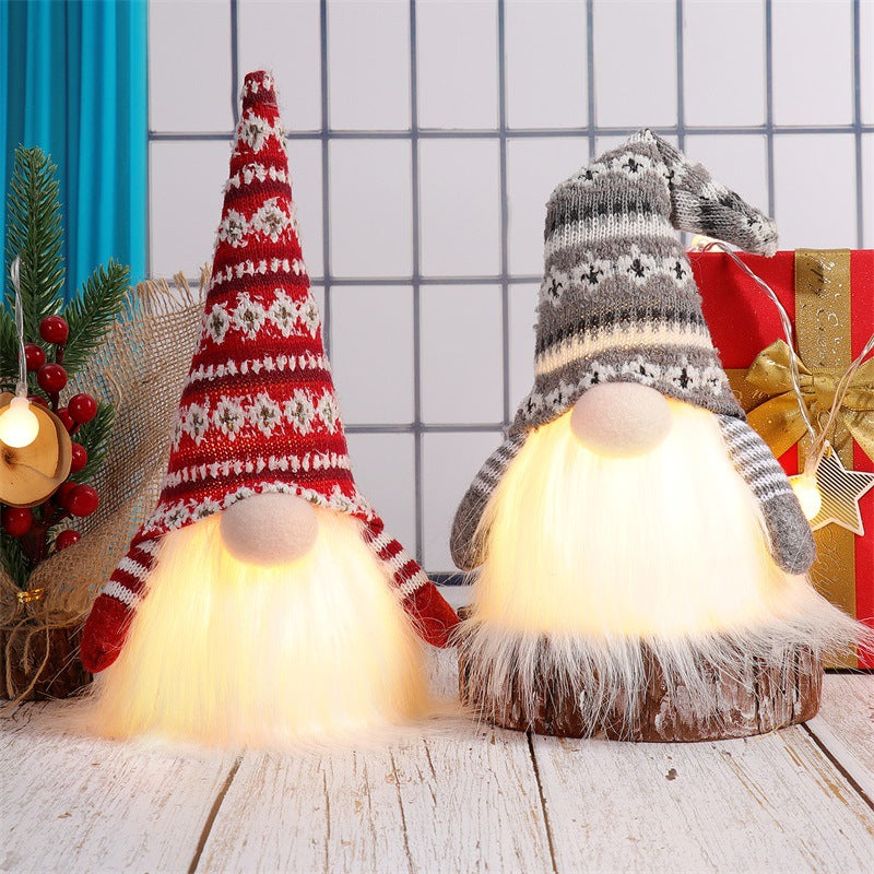 A knitted gnome light decoration with a warm glow, displayed next to a wrapped gift.