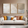 A set of three framed abstract canvas prints featuring beige and white textured mountain wave patterns displayed above a ligh