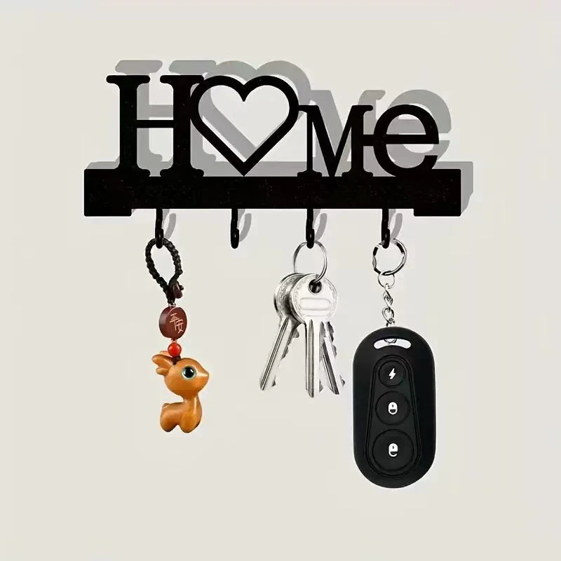 A black letter H and heart design metal wall key holder with four hooks and various keys.