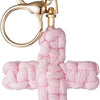 A pink woven cross keychain with a gold-toned split ring and clasp.