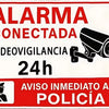 A red and white warning sign in Spanish indicating connected video surveillance 24h and immediate notification to the police.