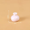 A small, round, pink resin vase with a narrow opening, shown against a beige background.
