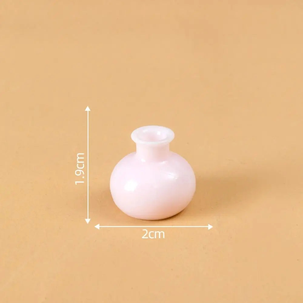 A small, round, pink resin vase with a narrow opening, shown against a beige background.