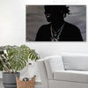 A black silhouette of a person wearing a necklace is displayed on a canvas against a light wall.