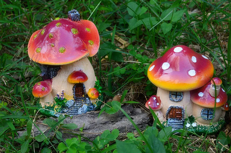 A resin mushroom house garden statue featuring a large red and white spotted toadstool with a small house structure.