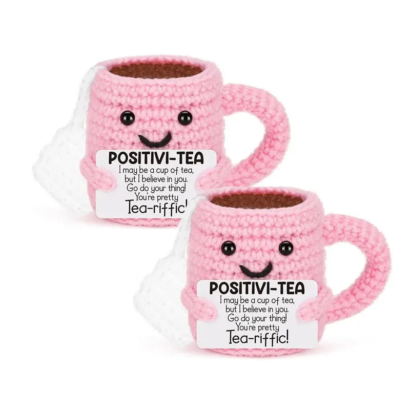 Pink crocheted tea cup ornament with a smiling face and motivational text