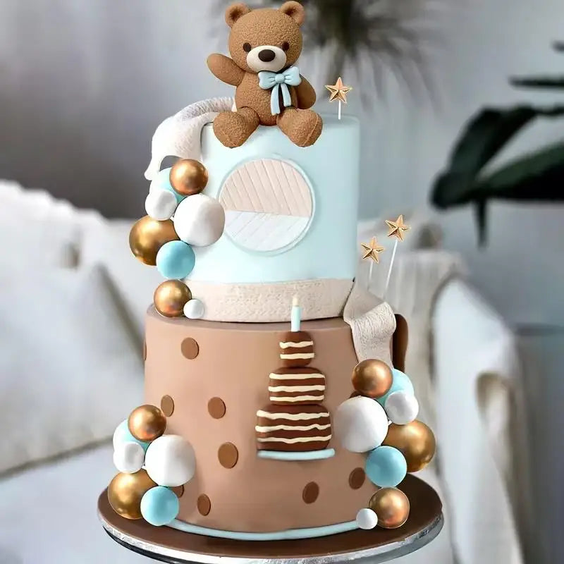A tiered cake decorated with teddy bear toppers, gold and white accents, and light blue frosting.