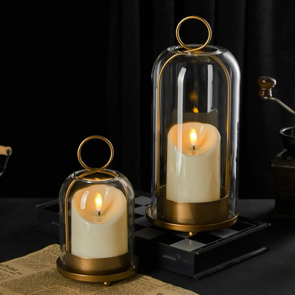 Antique brass metal candle holders with glass domes displaying white candles on a dark surface.
