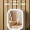 A white LED touch makeup mirror is displayed on a wooden surface, showing a reflection of a person's face.