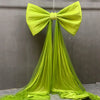 A bright lime green satin bow with long sheer tulle drapes, used for event decoration.