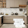 Modern kitchen featuring light beige cabinetry, white marble backsplash tiles, and stainless steel appliances.