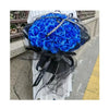 A bouquet of vibrant blue silk roses wrapped in black sheer fabric and ribbon.
