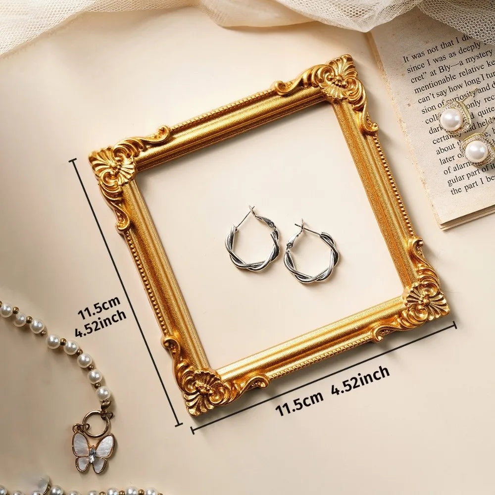 A vintage gold DIY shadow box frame with silver hoop earrings and a pearl necklace displayed on a light background.