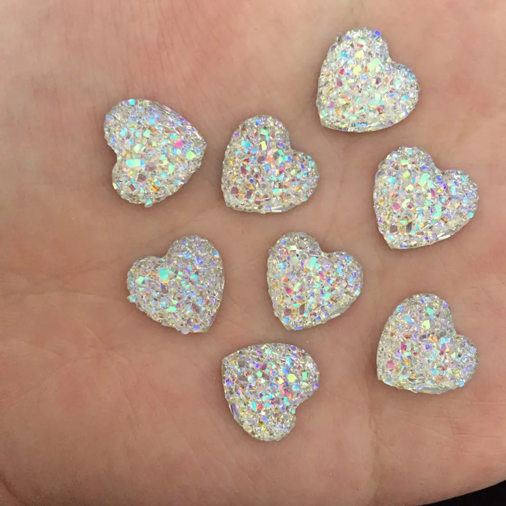 Eine Ansammlung kleiner, herzförmiger Strass-Ornamente auf einer Hand.