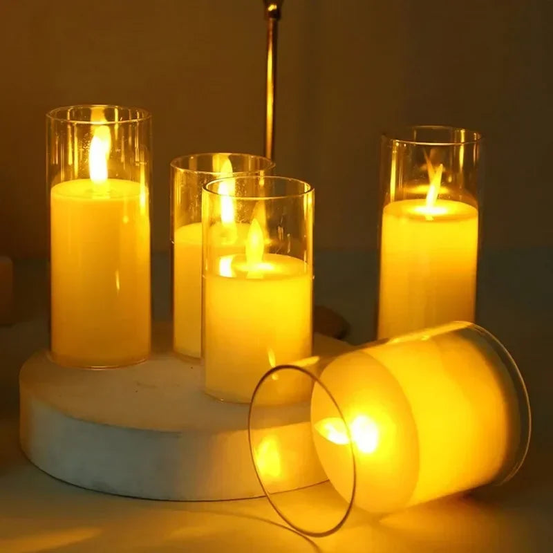 A collection of glowing yellow LED candles in glass holders with flickering flames on a light surface.