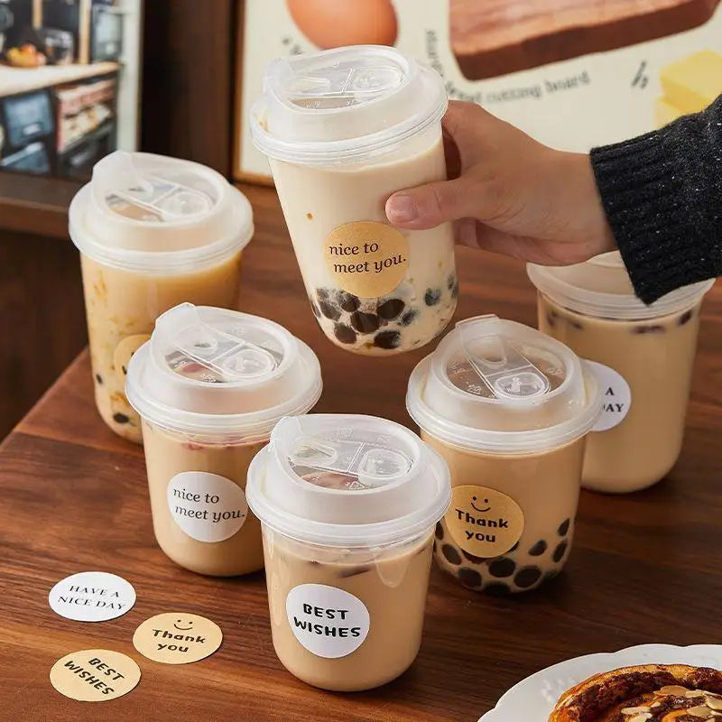 Several disposable coffee cups with lids filled with a light brown beverage and decorated with text like nice to meet you and