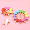A circular arrangement of small wooden heart clips in various pastel colors like pink, yellow, and green.