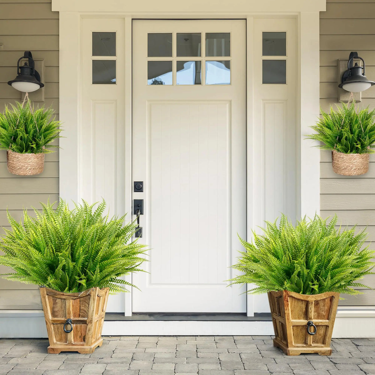 Two potted artificial Boston fern bushes flanking a white front door.