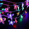 String lights featuring glowing butterfly shapes in various colors hanging against a dark background