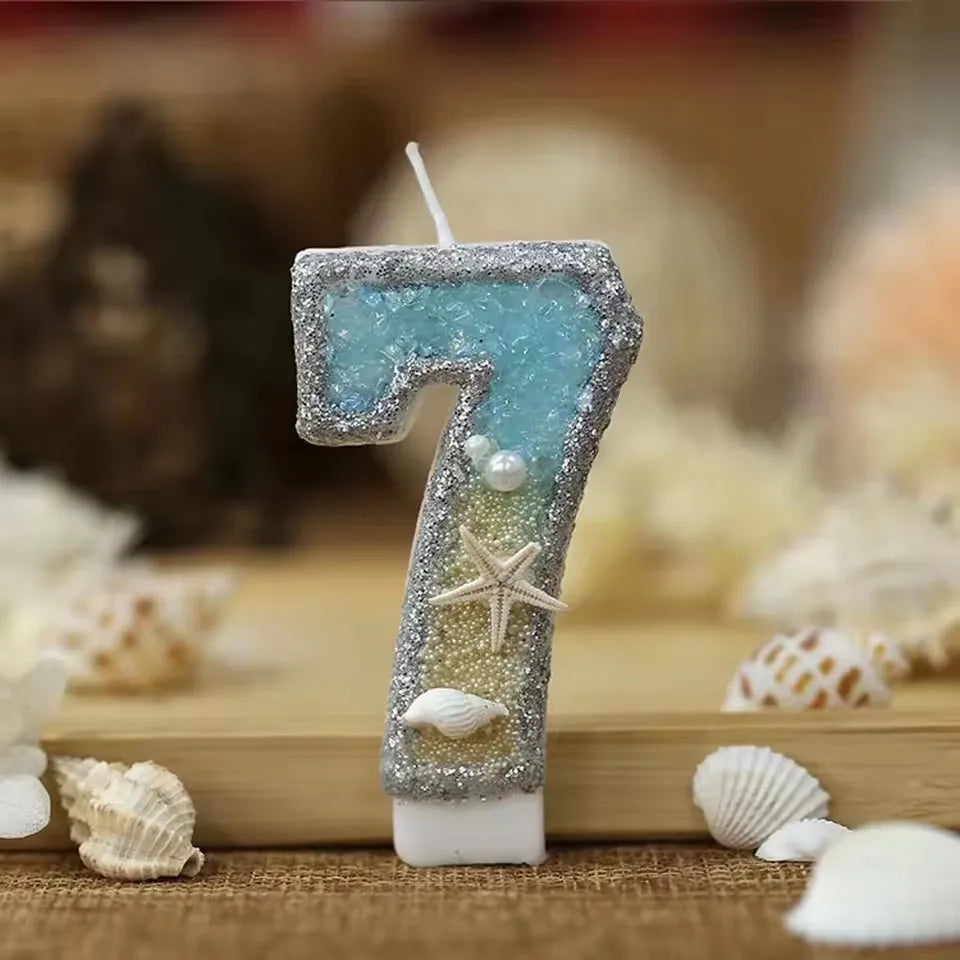 A glitter number cake topper shaped like the number 7 with a starfish design, set against a blurred background of white sea s