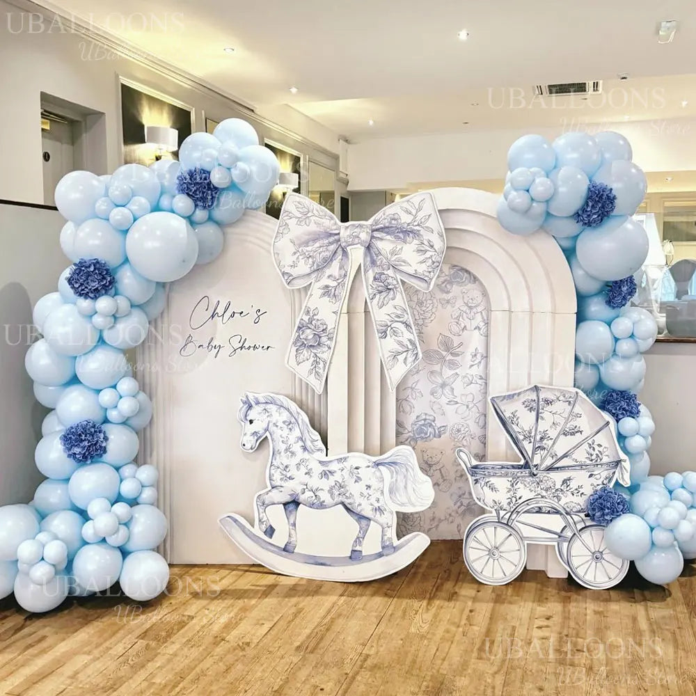 A white balloon arch decorated with light blue and purple balloons and a horse silhouette for a baby shower