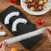 A hand holds a clear reusable food storage bag with decorative bows on a black cutting board next to fresh tomatoes.