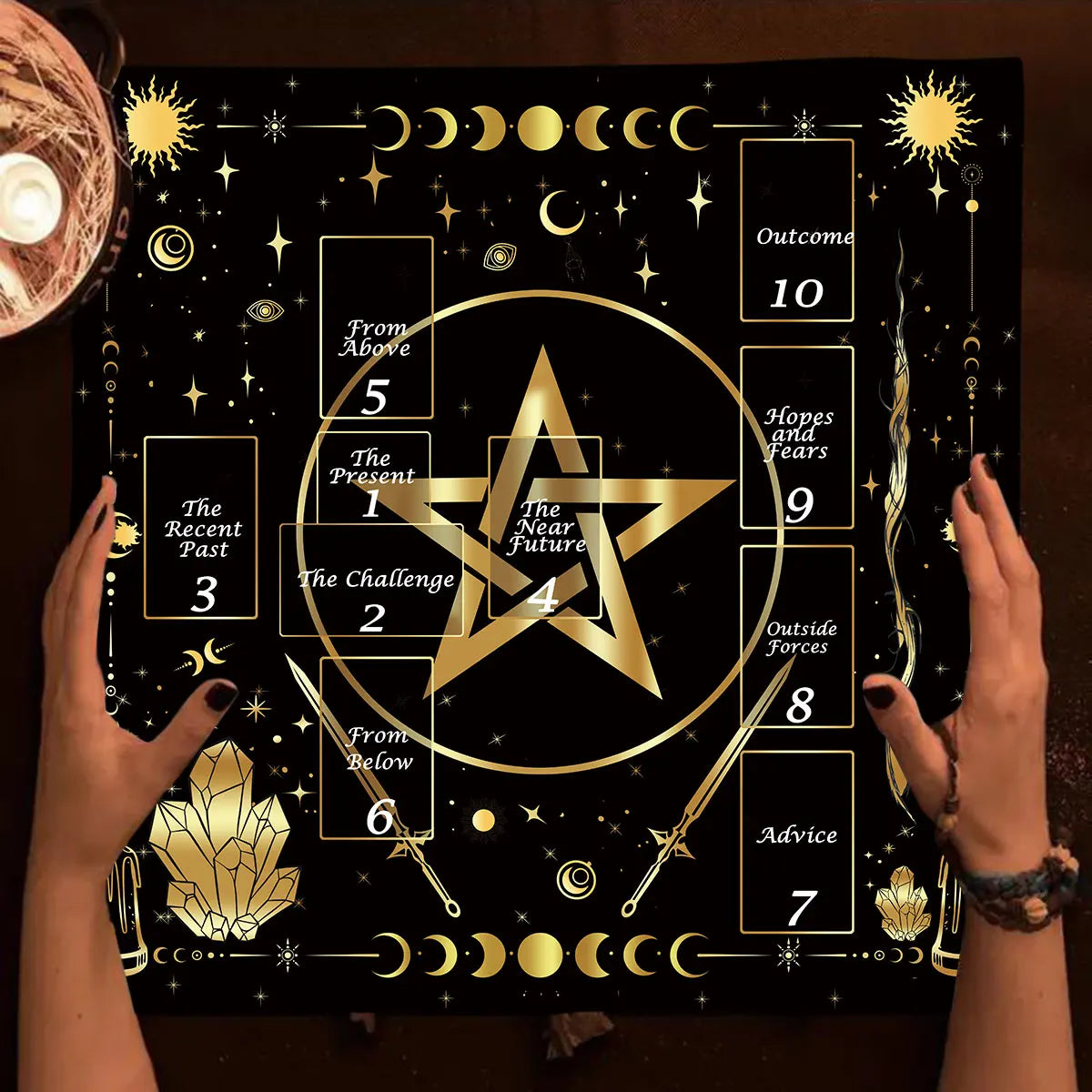 Hands holding a black altar cloth featuring the Celtic Cross symbol and astrological symbols for tarot divination