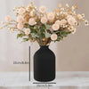 A large matte black decorative vase filled with dried light pink and beige floral arrangements.
