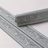Close-up view of silver self-adhesive foam wall trim strips with embossed leaf patterns.