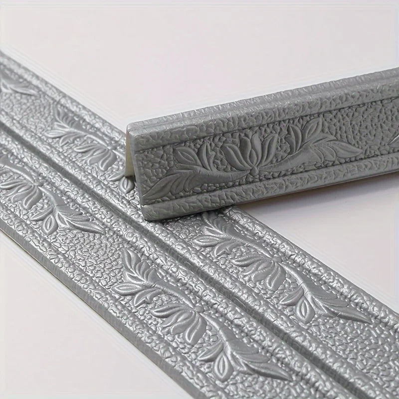 Close-up view of silver self-adhesive foam wall trim strips with embossed leaf patterns.
