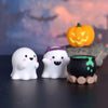 Three white ghost resin miniatures with purple accents are displayed next to an orange pumpkin on a dark surface.