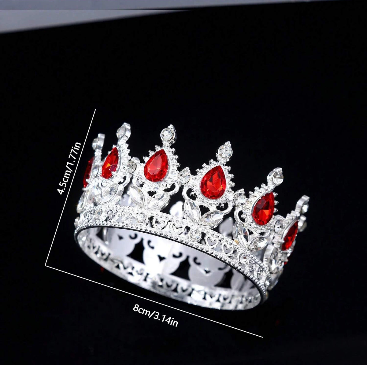 Silver crystal rhinestone crown ring with red gemstones shown against a black background.