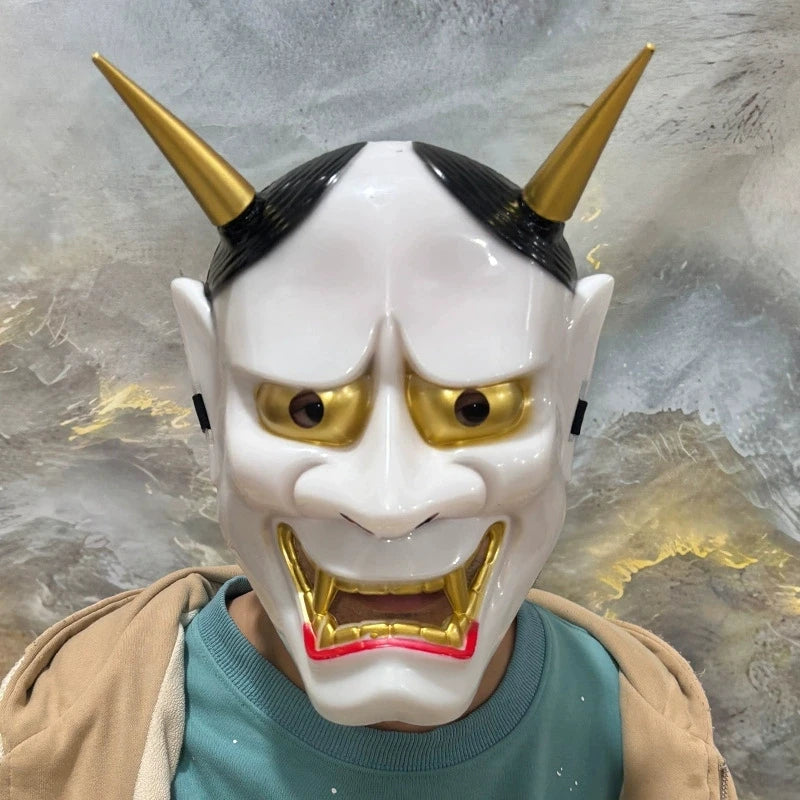 A full face Japanese Hannya demon mask with white skin, golden horns, and fierce facial expression.