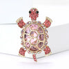 A vintage marine life brooch pin set featuring a pink and gold turtle design with sparkling accents.