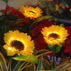 A close-up of a bright yellow solar sunflower LED garden light flower blooming in a dark garden setting.