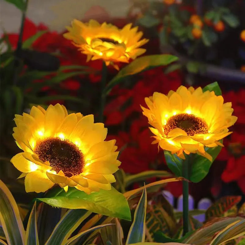 A close-up of a bright yellow solar sunflower LED garden light flower blooming in a dark garden setting.