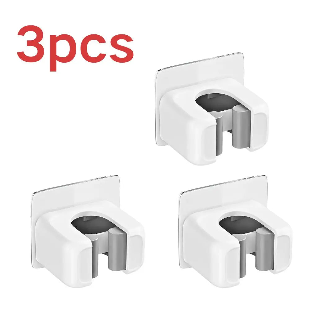 Three white self-adhesive wall holders for storing mops, brooms, and long-handled tools.