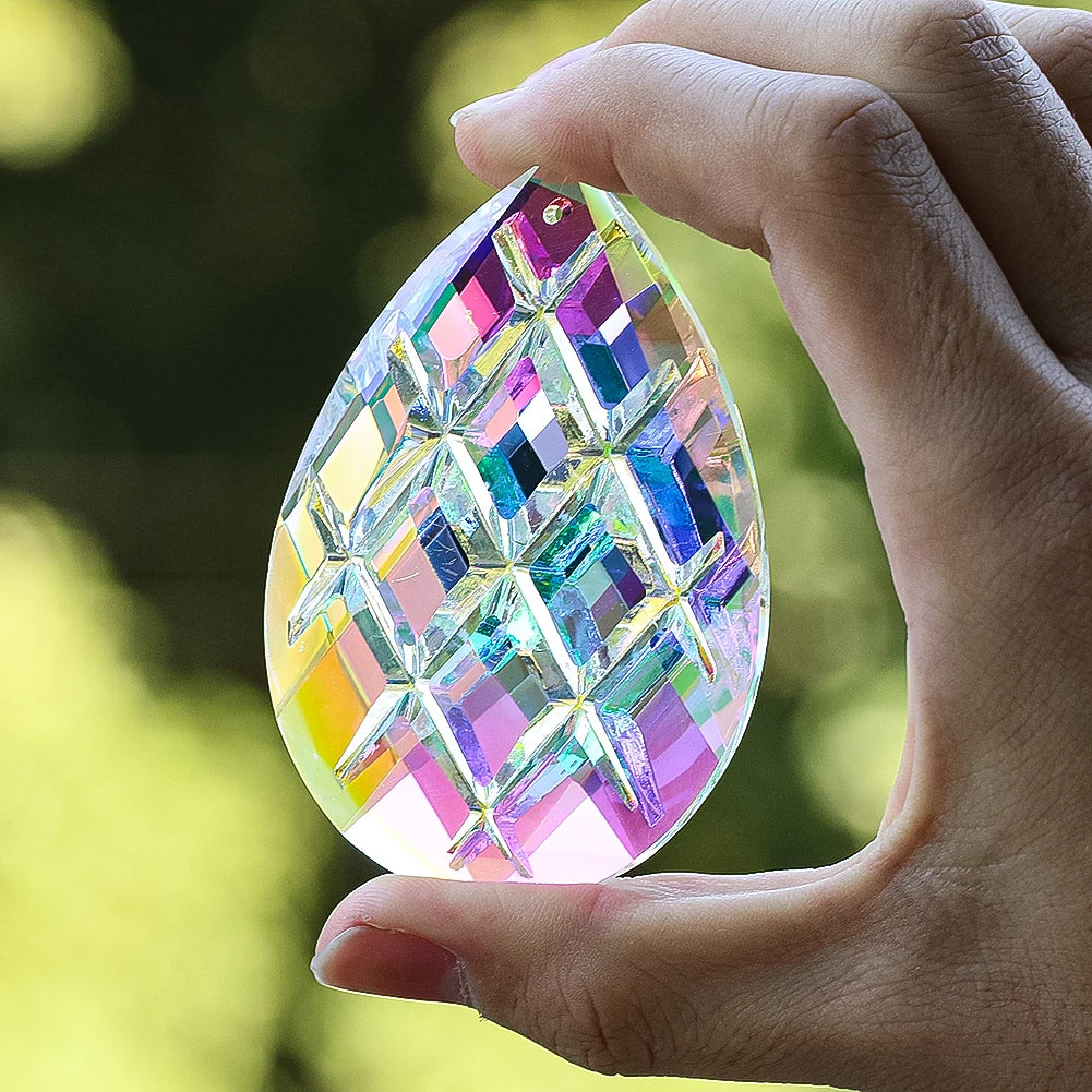 A hand holds a faceted crystal prism with iridescent colors, catching light and displaying geometric patterns.