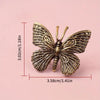 Handcrafted brass rooster figurine with intricate details shown against a pink background.