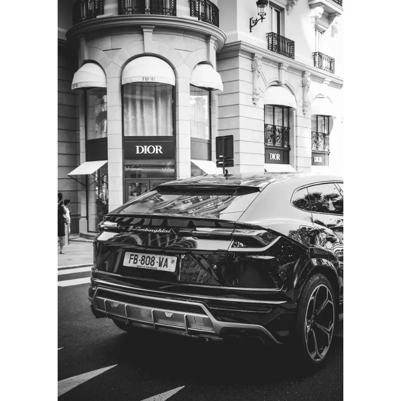 Ein schwarzes Luxusauto parkt vor einem Dior-Geschäft mit Rundbögen.