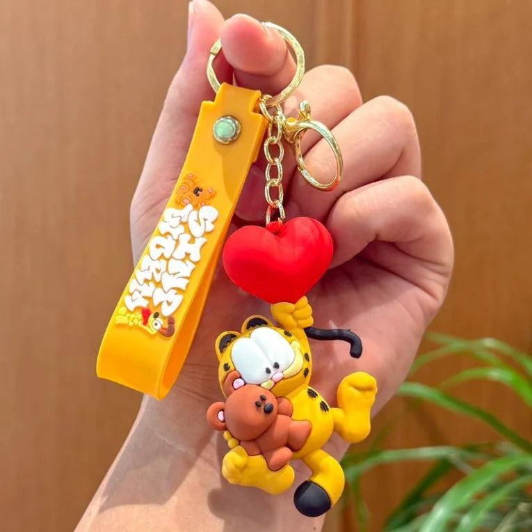 A hand holds a yellow keychain pendant featuring a Garfield cartoon character.