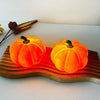 An orange decorative LED pumpkin night light resting on a wooden surface.