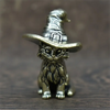Vintage brass cat statue wearing a witch hat, sitting on a wooden surface.