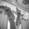 A close-up shot of a woman's legs and feet wearing sparkling diamond-encrusted high heels in an ornate interior.