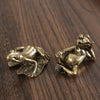 Antique brass frog sculpture decor resting on a dark wooden surface.