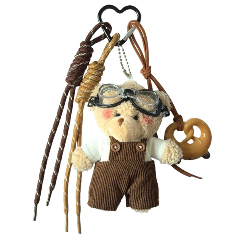 Un ours en peluche brun avec des lunettes attaché à une clé USB aviateur en cuir.