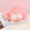 A pink Lucas the Spider plush toy with large eyes and soft fur resting on a white box.