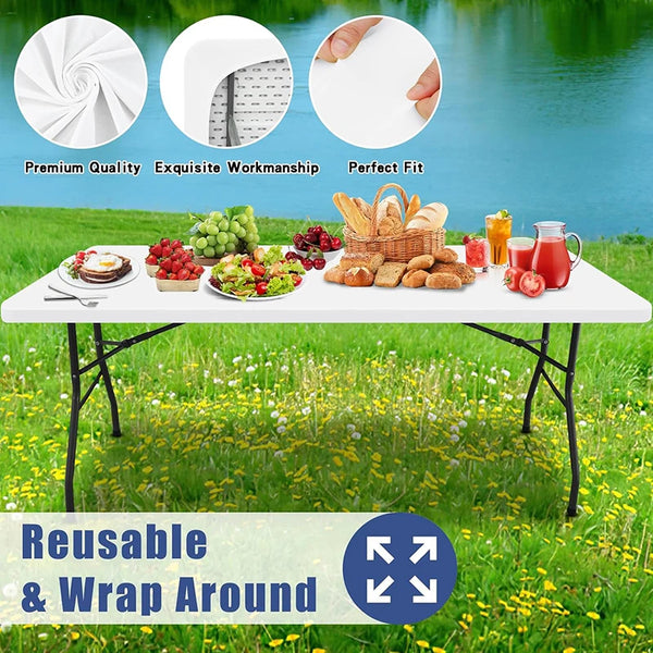 White reusable stretch tablecloths set displayed outdoors on a table with food and greenery.
