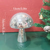 A mushroom-shaped disco ball decoration made of silver mosaic tiles, shown against a red background with a green Christmas tr