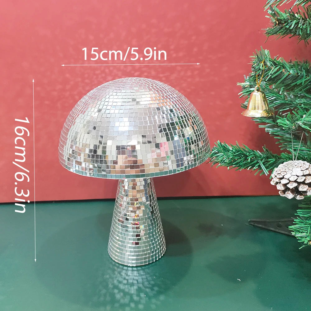 A mushroom-shaped disco ball decoration made of silver mosaic tiles, shown against a red background with a green Christmas tr